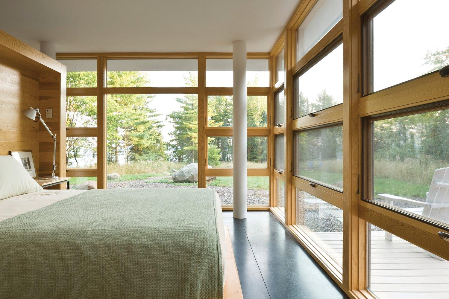 Bedroom surrounded by windows with warm wood frames