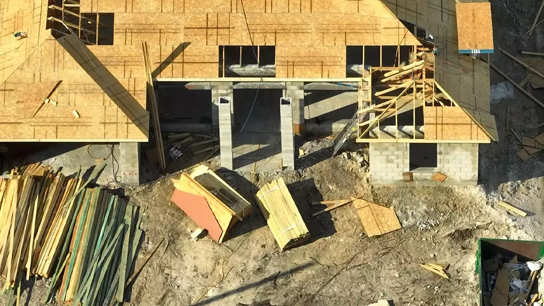 Overview of House Under Construction with Materials and Scattered Debris